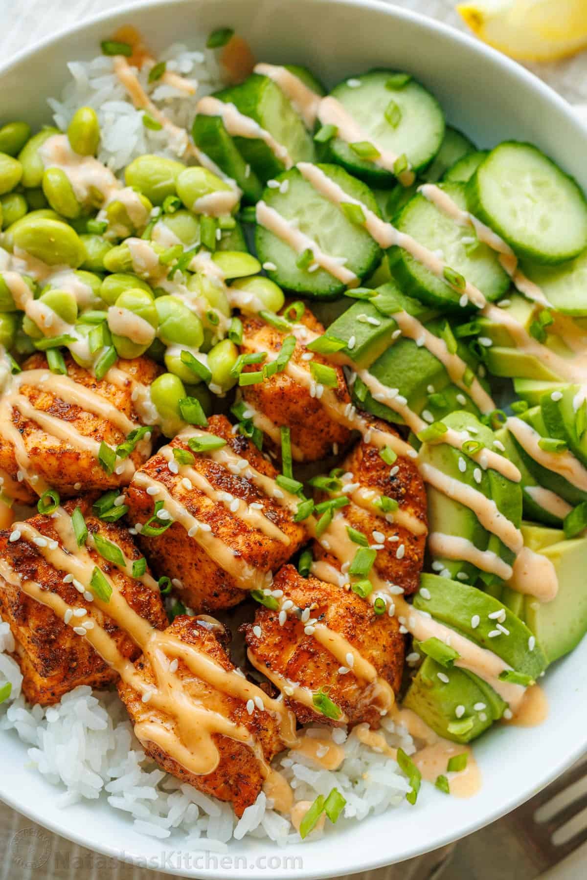 salmon rice bowl with sliced vegetables and drizzled with orange sauce