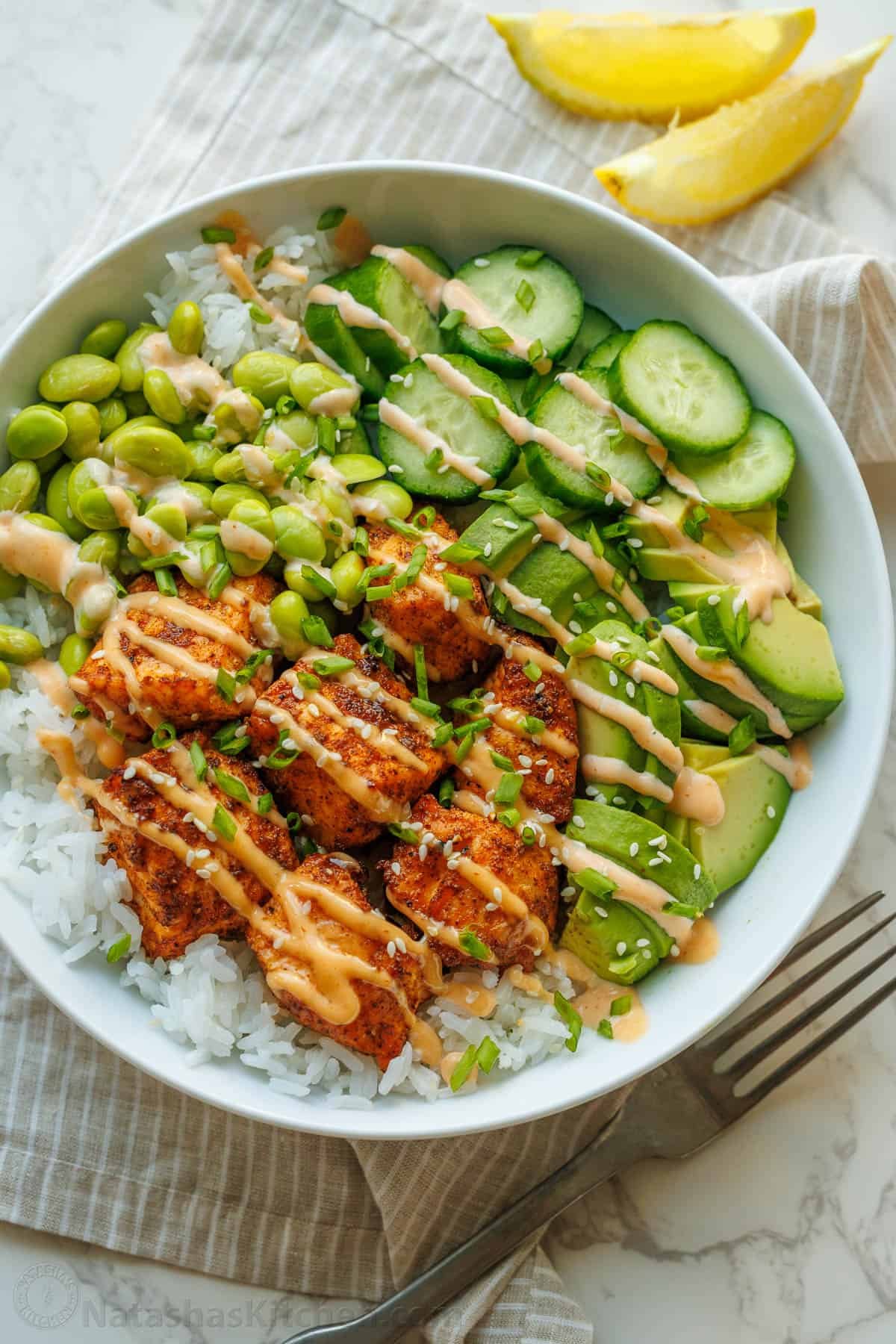 Salmon bowls recipe in a large bowl with mayo sauce drizzled over the top