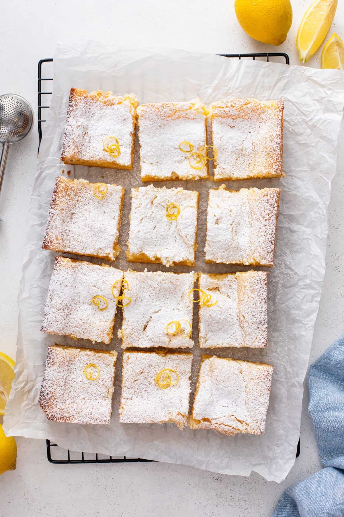 Overhead view of sliced lemon gooey butter cake. The top of the cake is dusted with powdered sugar.