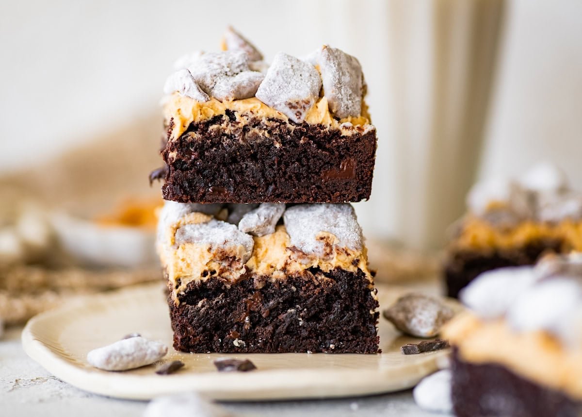 two puppy chow brownies stacked on a plate.