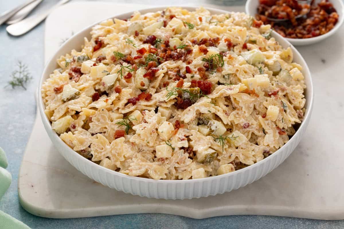 Serving bowl filled with dill pickle pasta salad, topped with crumbled bacon.