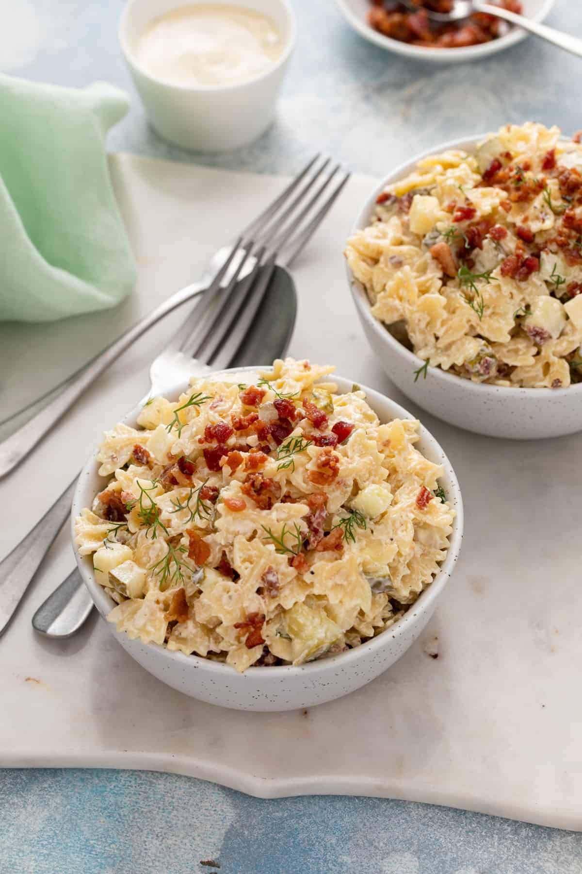 Two small serving bowls each filled with dill pickle pasta salad.