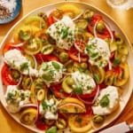 Tomato salad on a plate with herbs on the side.