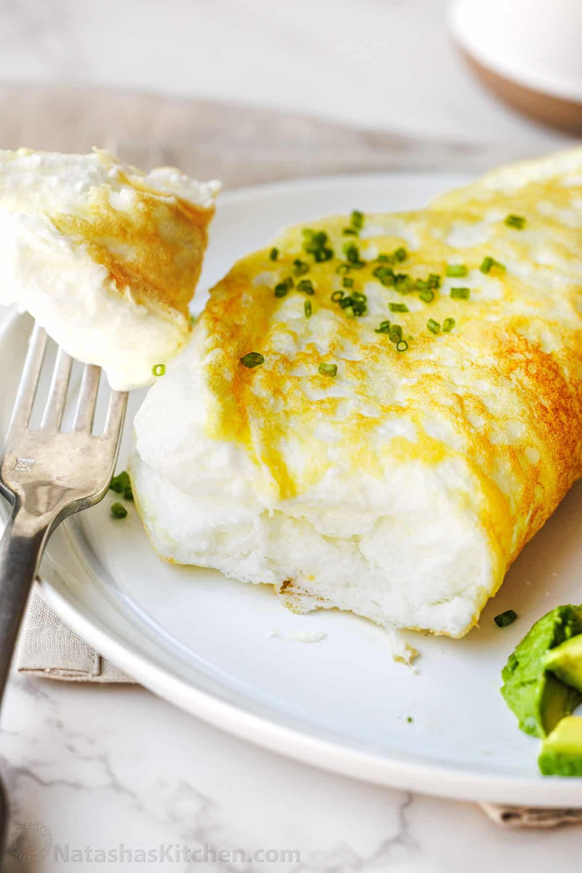 Make a fluffy egg white omelette in just 10 minutes with 4 ingredients. It’s light, airy, high-protein, and easy to customize with toppings. A fork with a bite of Soufflé egg white omelette cut off the omelette