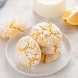 Four lemon crinkle cookies on a white plate.