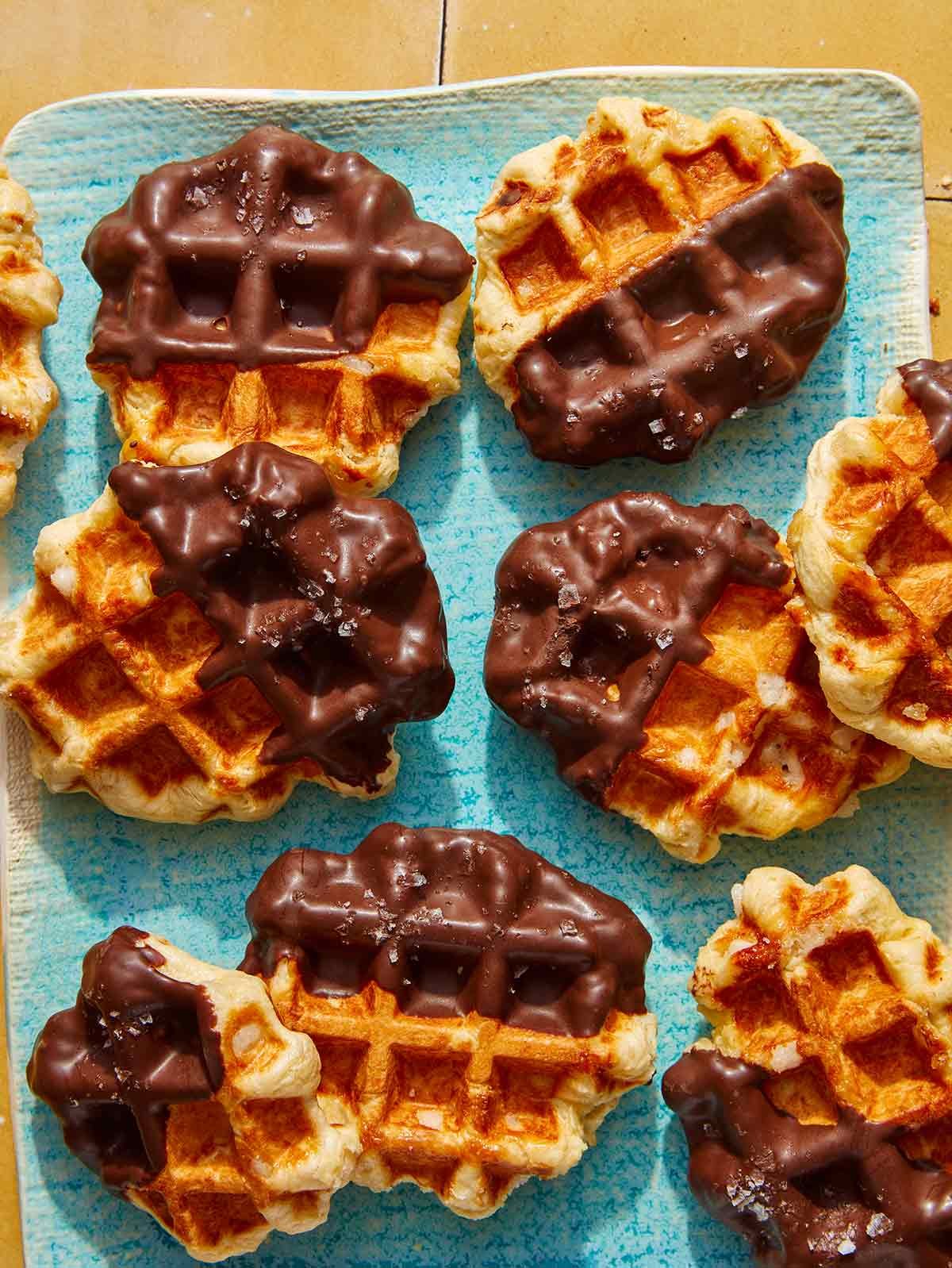 Close up view of a platter of liege waffles dipping in chocolate.