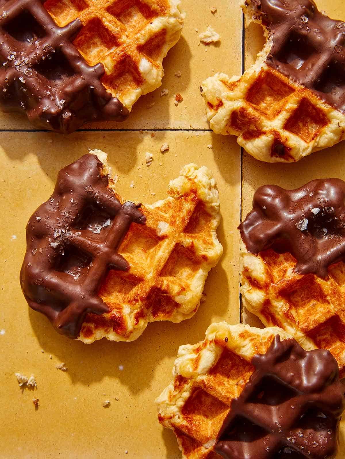 Partially eaten liege waffles with bites taken out of them on a kitchen counter.