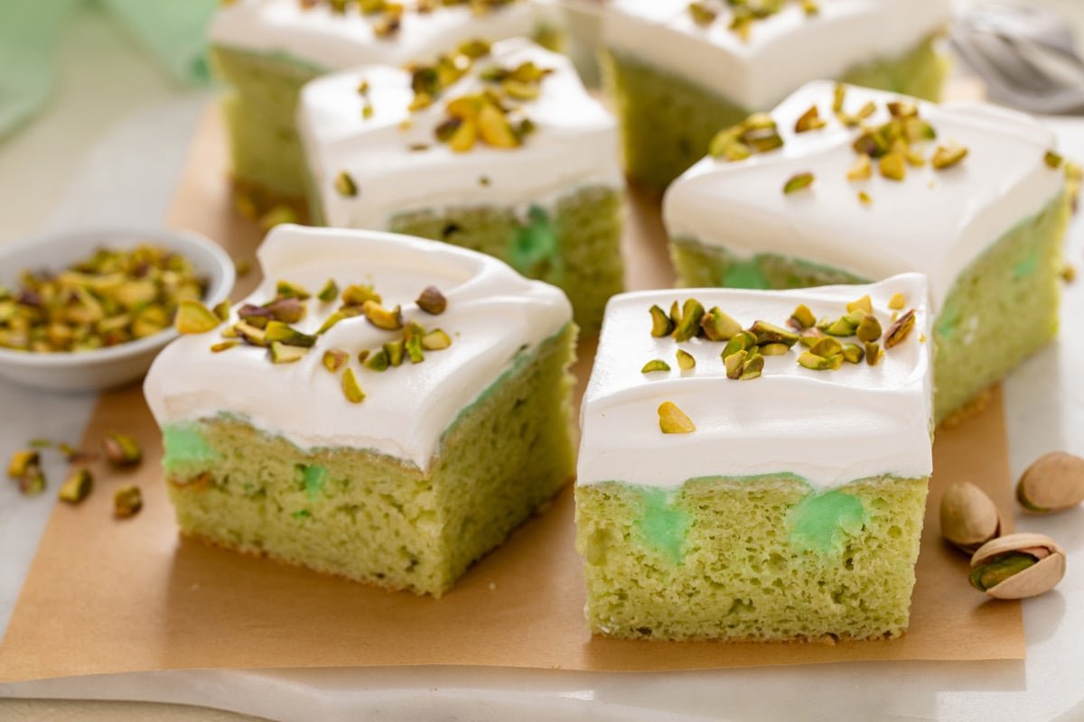 Slices of pistachio poke cake topped with chopped pistachios.