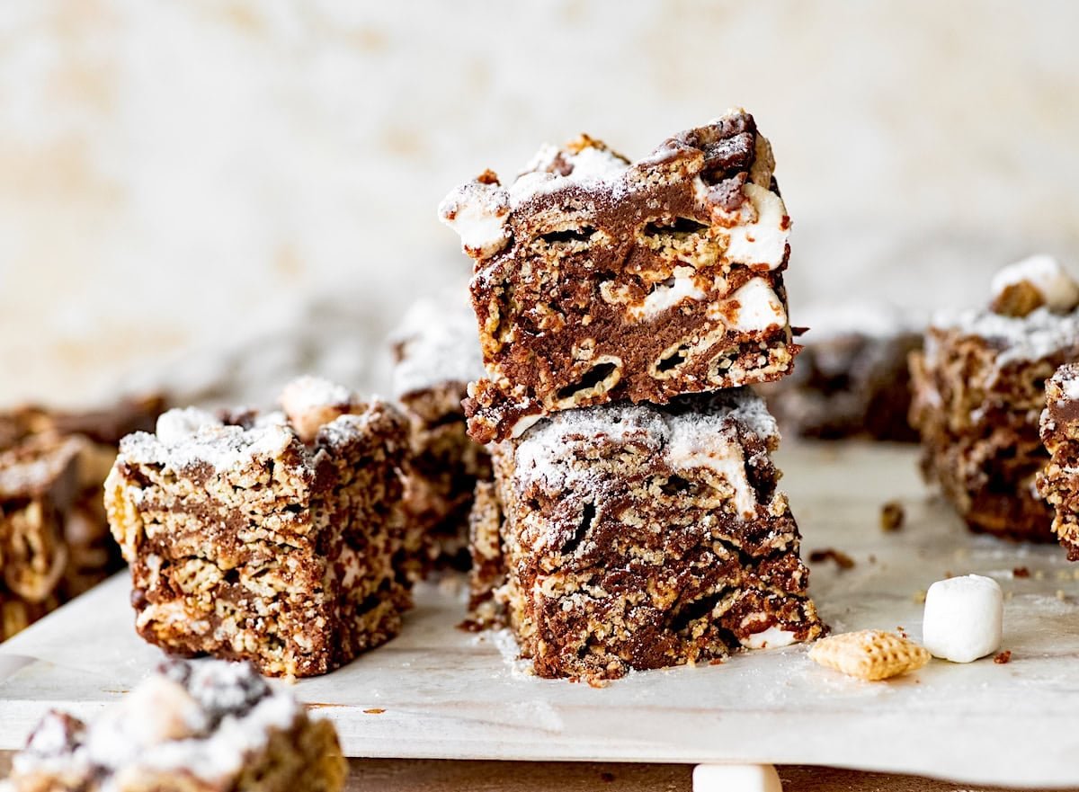 puppy chow marshmallow treats cut into squares and stacked. 