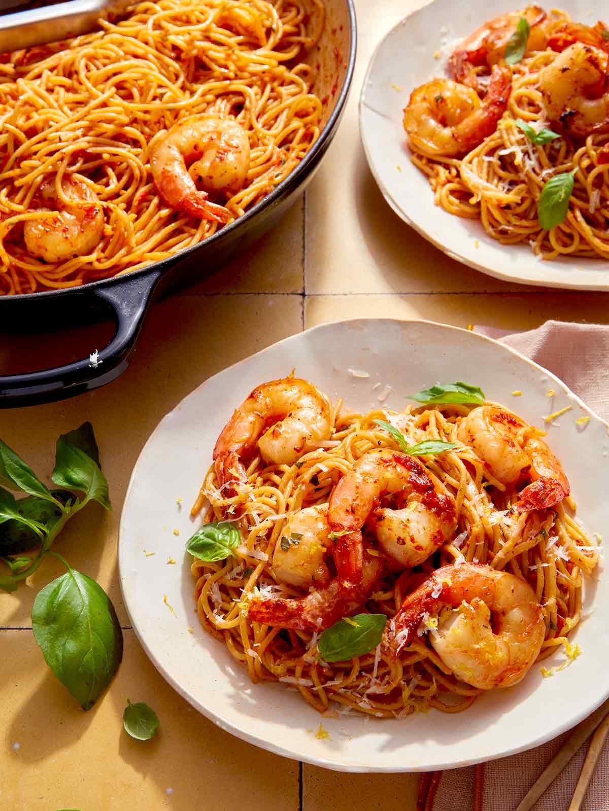 Tomato butter pasta with shrimp being served from a skillet.