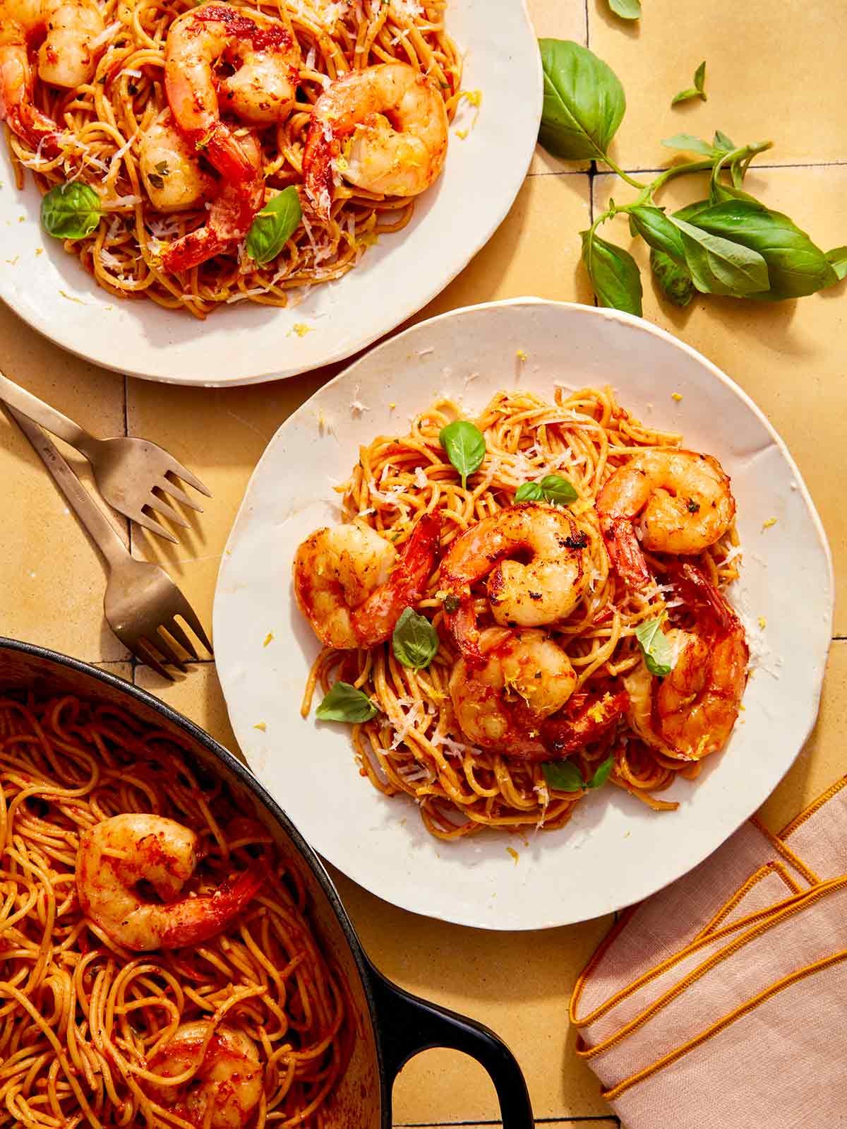 Tomato butter pasta with shrimp being served from a skillet.
