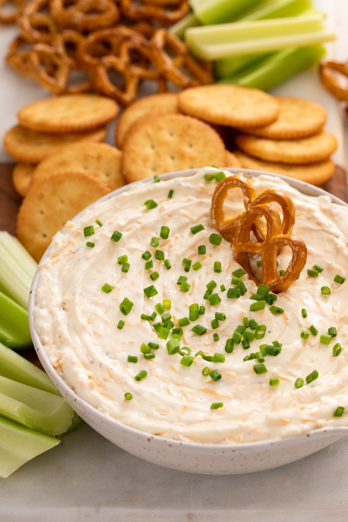 Two pretzel twists tucked into beer cheese dip in a white bowl.