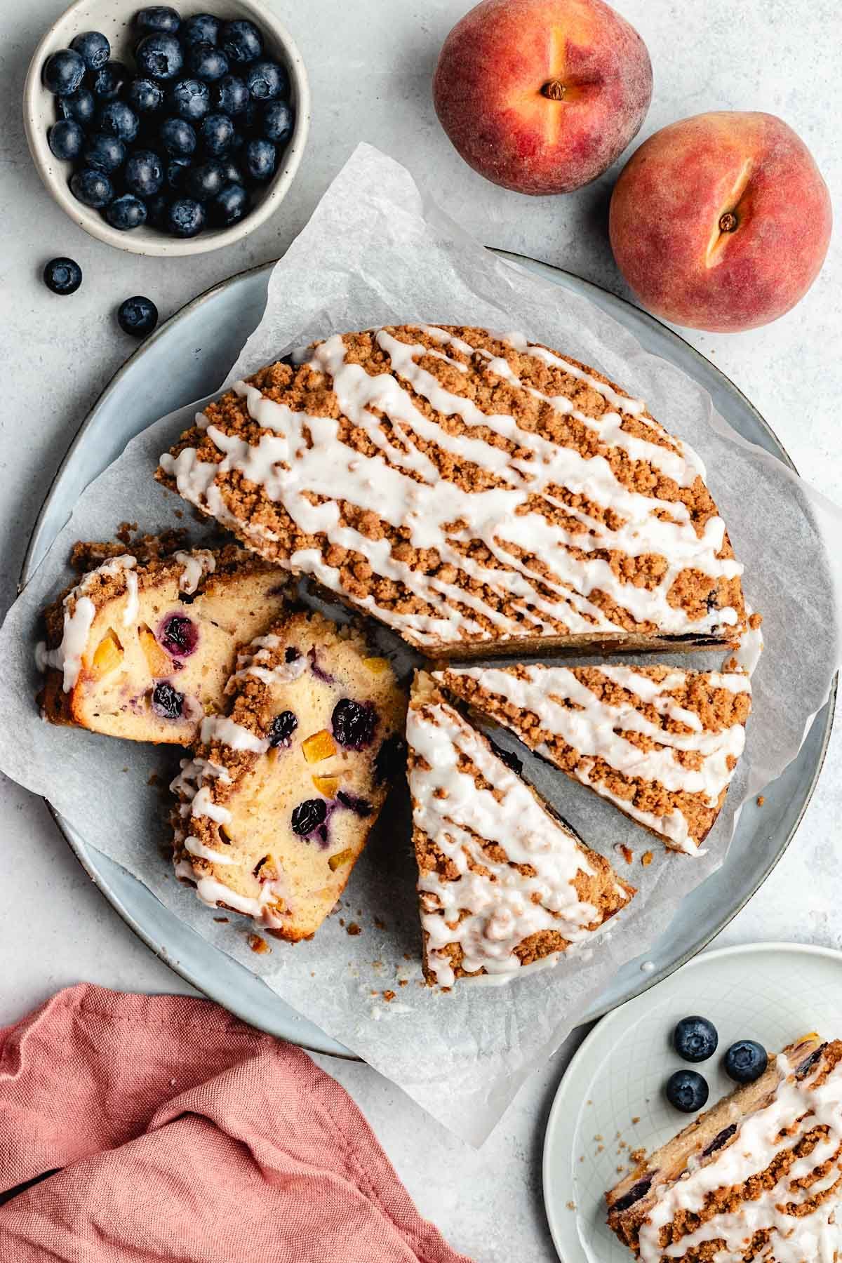 peach blueberry cake with streusel topping and glaze cut into pieces. 