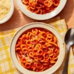 Homemade Spaghetti Os in two bowl with parmesan on the side.