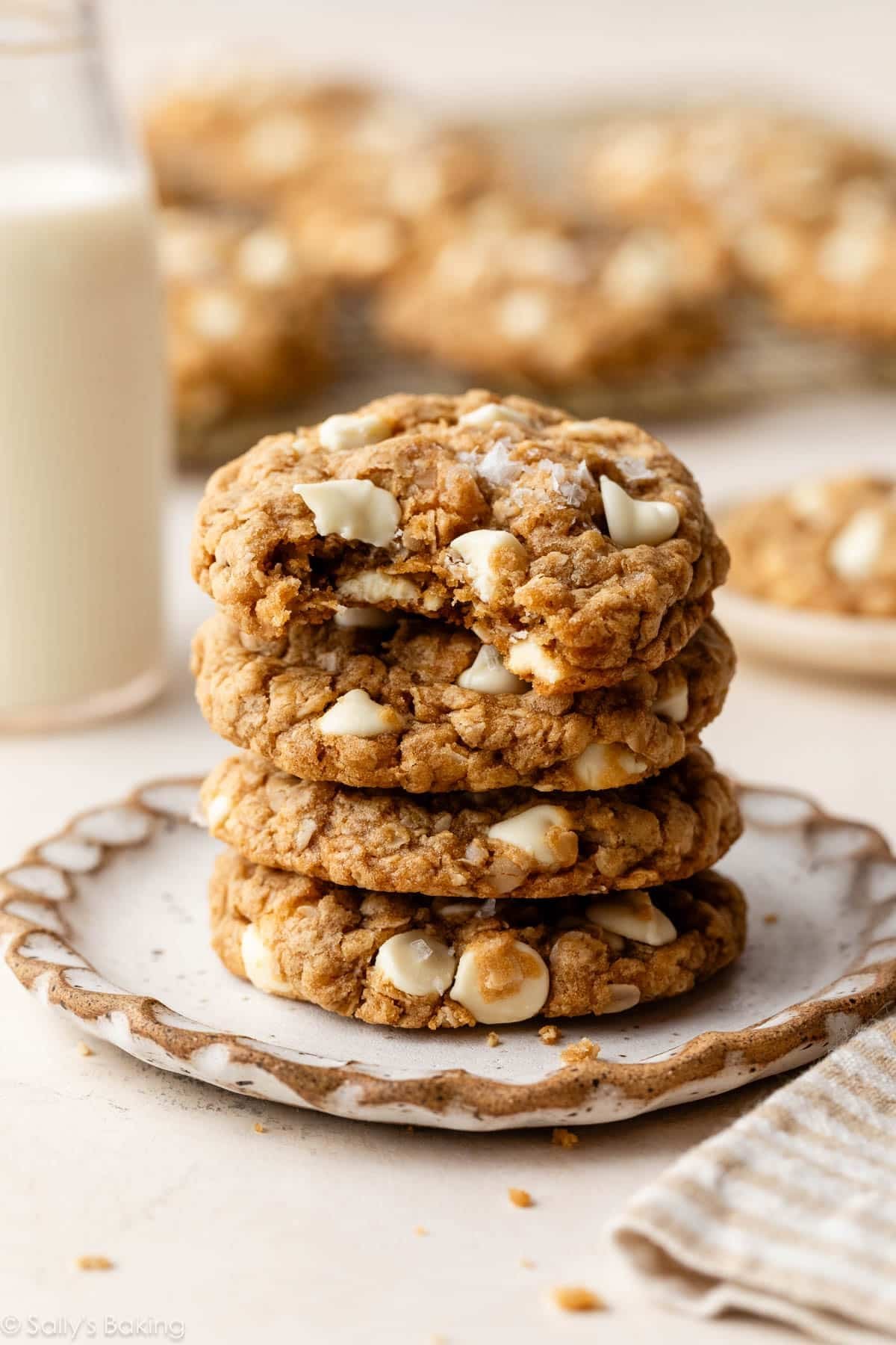 stack of 4 Biscoff white chocolate oatmeal cookies on a plate with a bite taken out of one cookie.