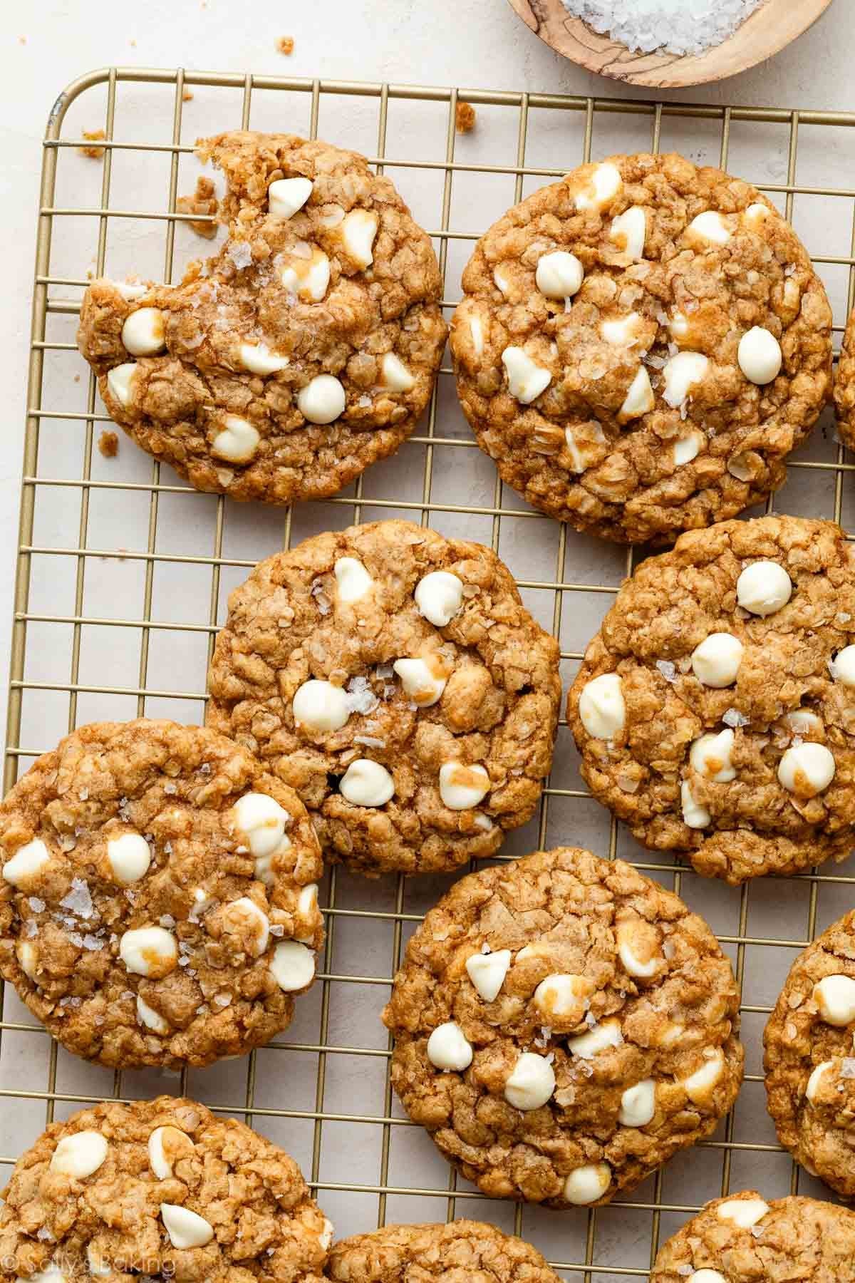 Biscoff white chocolate oatmeal cookies on a cooling rack with a bite taken out of one cookie.