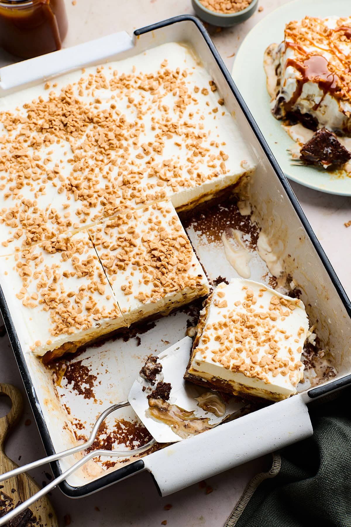 salted caramel toffee brownie ice cream cake in pan with pieces being cut.