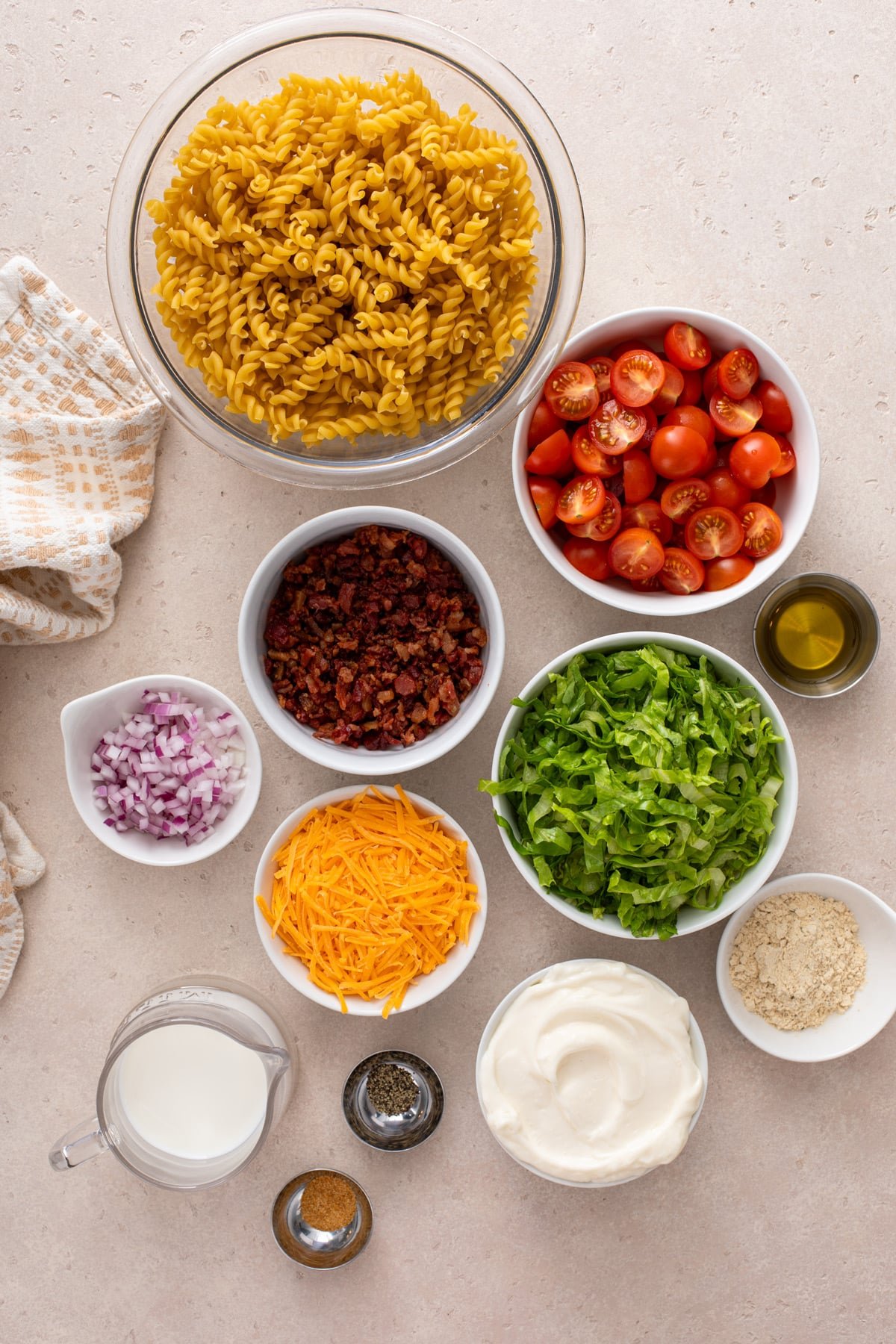 Ingredients for BLT pasta salad arranged on a countertop.