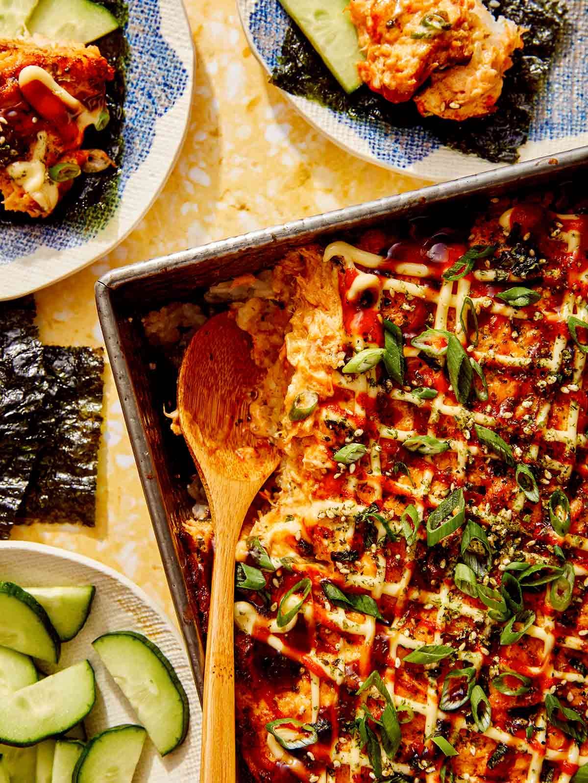 Salmon sushi bake in a baking dish with a spoon in it.