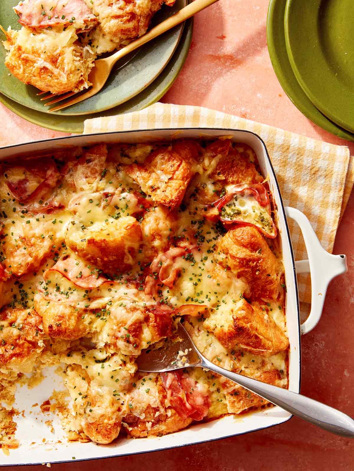 A croissant bake with a spoon it in serving onto plates.