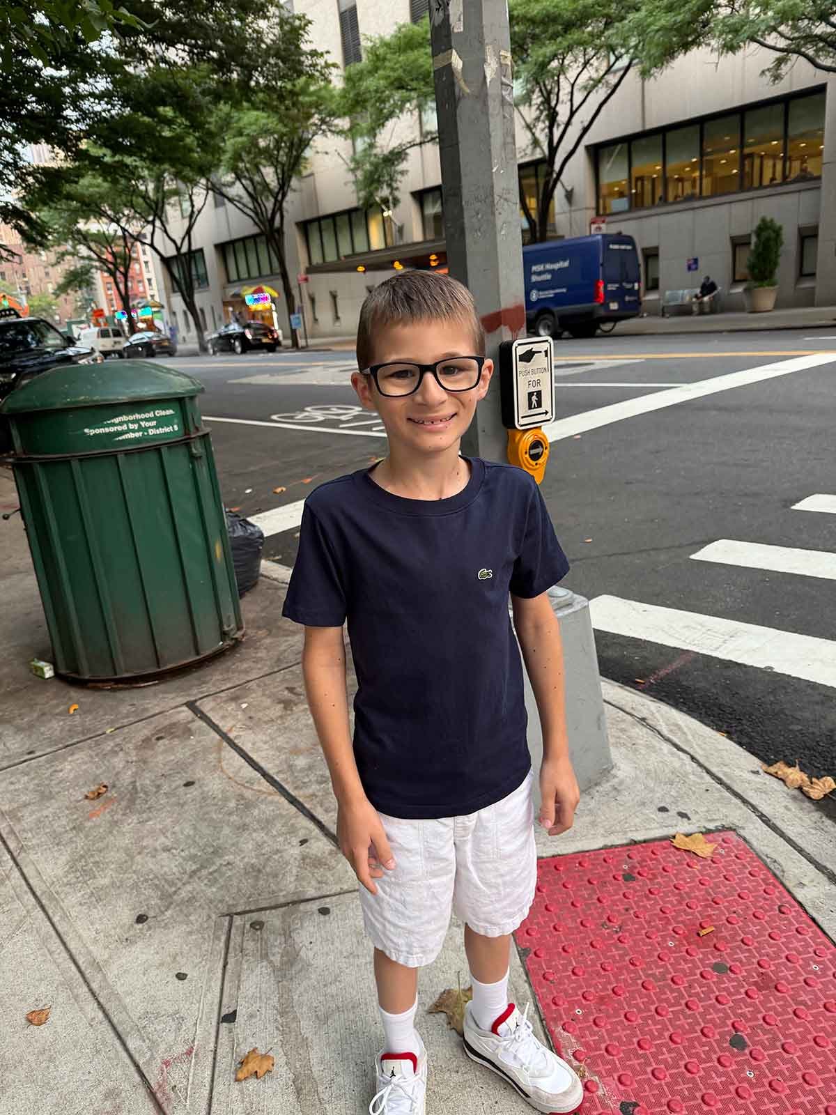 Little boy standing on a street corner in New York City.