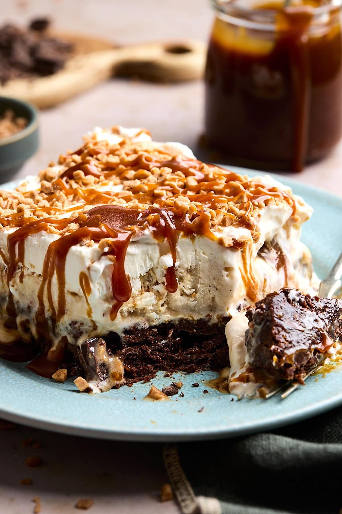 close up of piece of salted caramel toffee brownie ice cream cake on plate with fork.