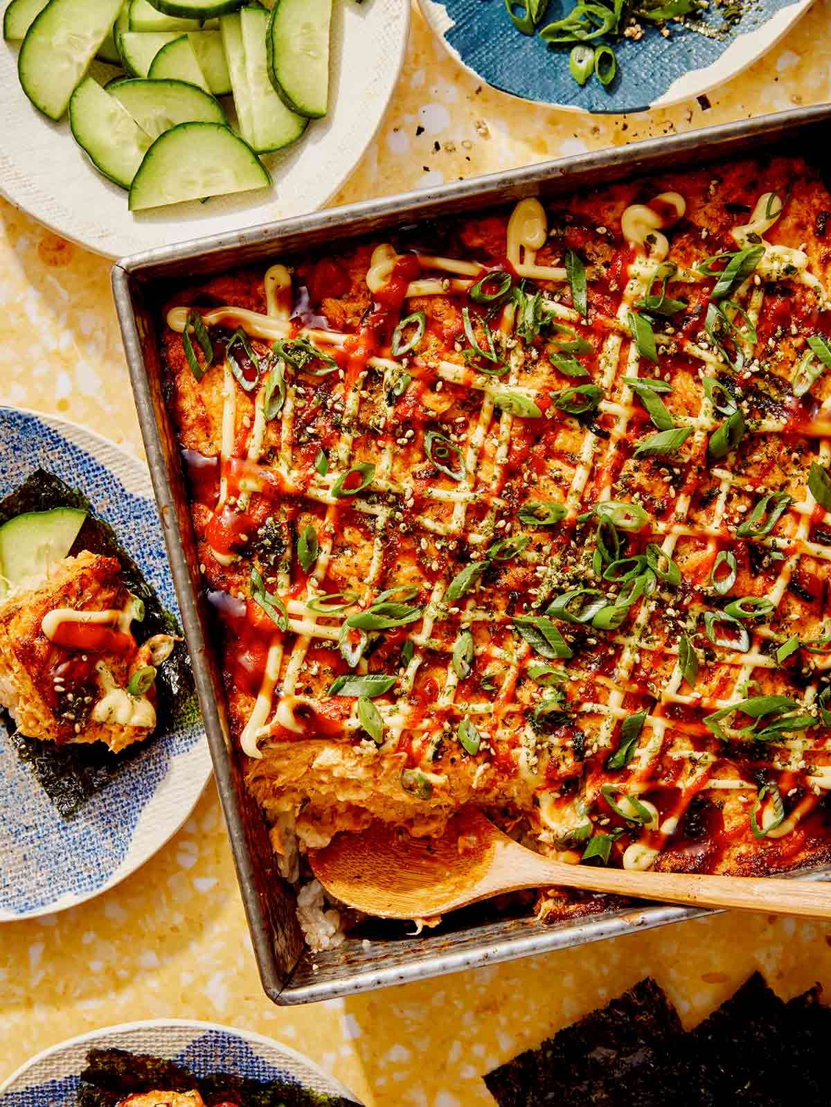 Salmon sushi bake in a baking dish with cucumbers and nori. 