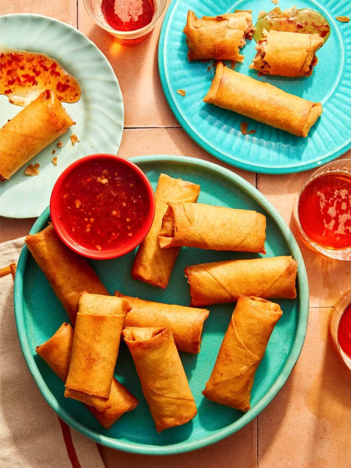 Vietnamese spring rolls on a platter with a bowl on sweet chili sauce. 