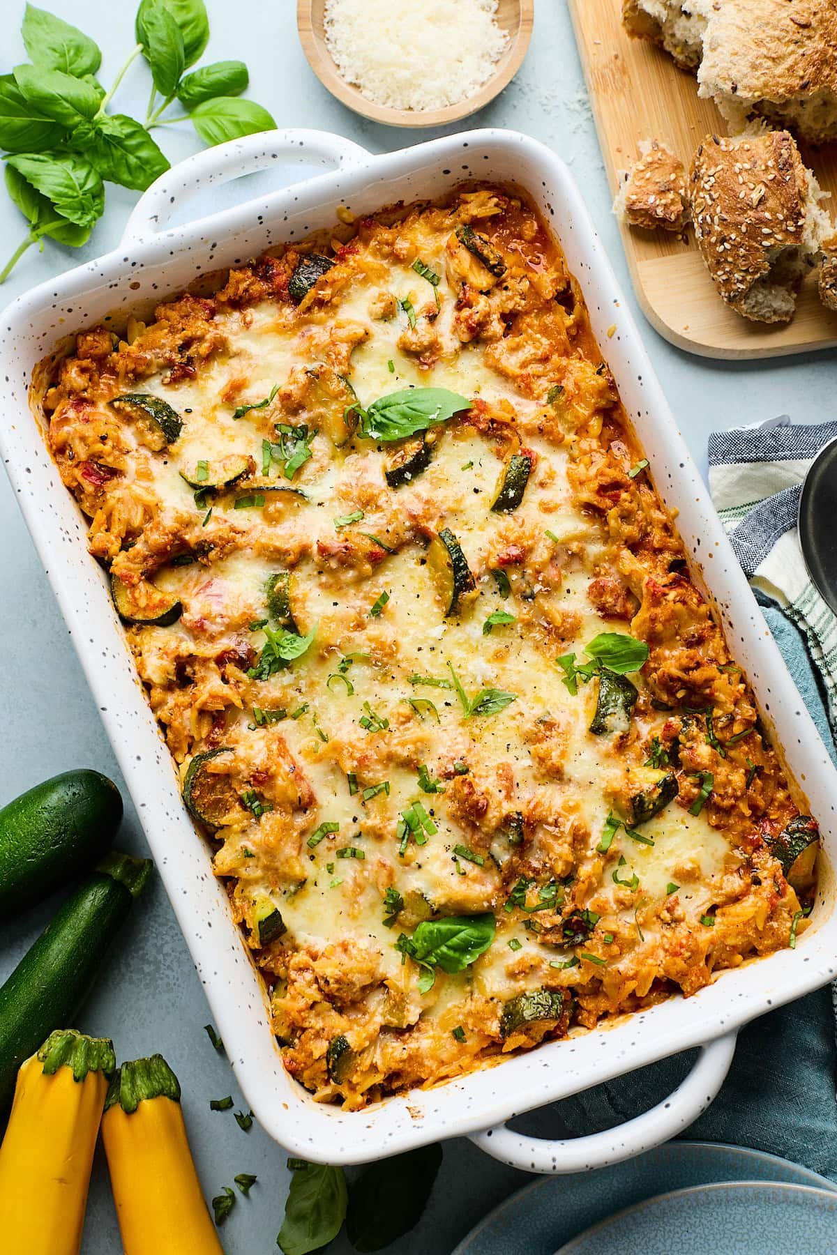 zucchini casserole in pan with melty cheese and fresh basil.