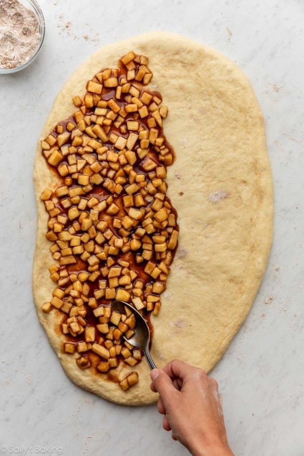 spreading apple filling on dough.