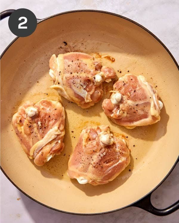 Chicken thighs being seared in a skillet.
