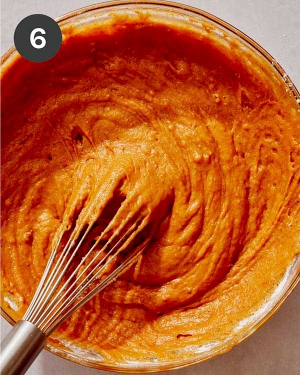 Pumpkin cake batter being mixed together in a glass bowl.